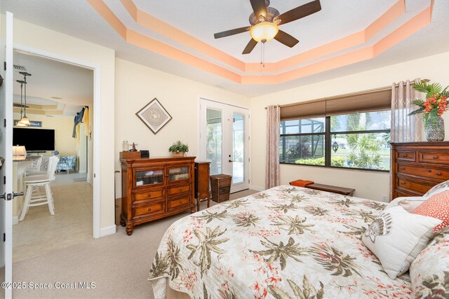 679 Sheridan Woods Dr, Melbourne, FL 32904 - bedroom featuring access to exterior, light carpet, a tray ceiling, and baseboards