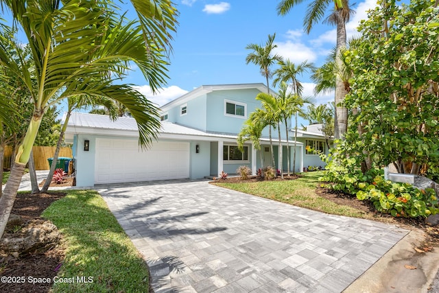 view of front of house with stucco siding, decorative driveway, an attached garage, and fence