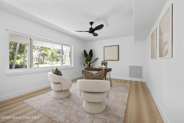 living area with a ceiling fan, light wood-style floors, and baseboards