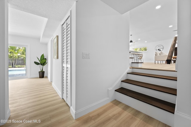 stairs featuring wood finished floors, healthy amount of natural light, baseboards, and recessed lighting