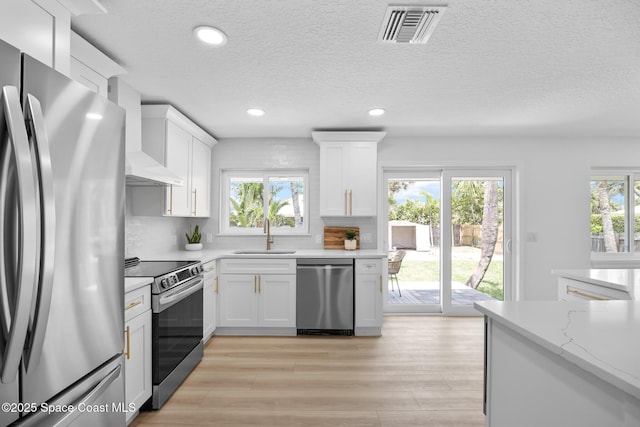 kitchen with stainless steel appliances, a sink, white cabinets, recessed lighting, and light wood-style flooring