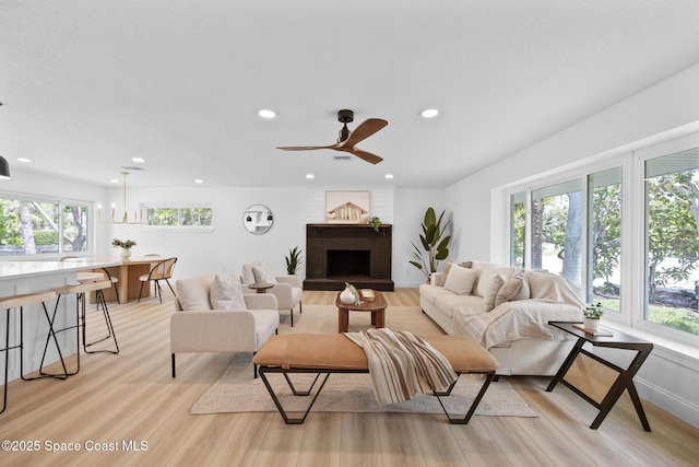 living area with light wood-style floors, recessed lighting, a brick fireplace, and ceiling fan