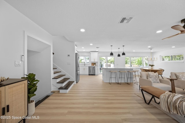 living room with light wood-type flooring, recessed lighting, and stairs