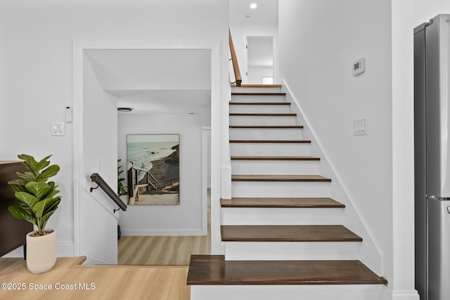 stairway with wood finished floors and baseboards