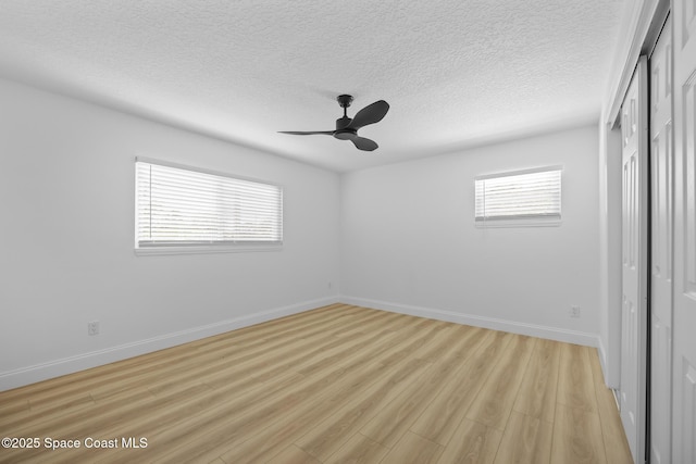 unfurnished bedroom with a closet, light wood-style floors, baseboards, a textured ceiling, and a ceiling fan
