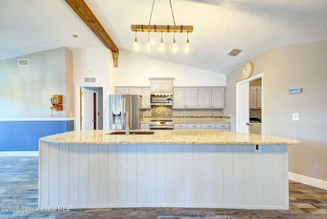 kitchen with appliances with stainless steel finishes, wood finished floors, a sink, baseboards, and backsplash