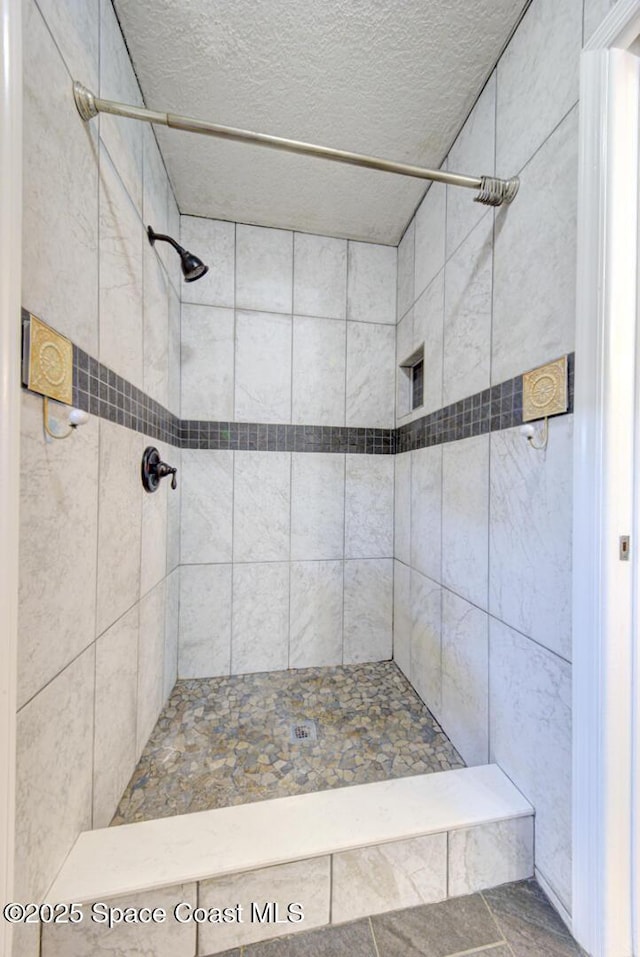 full bathroom featuring tiled shower and a textured ceiling