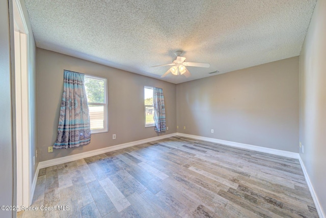 unfurnished room featuring ceiling fan, wood finished floors, a textured ceiling, and baseboards