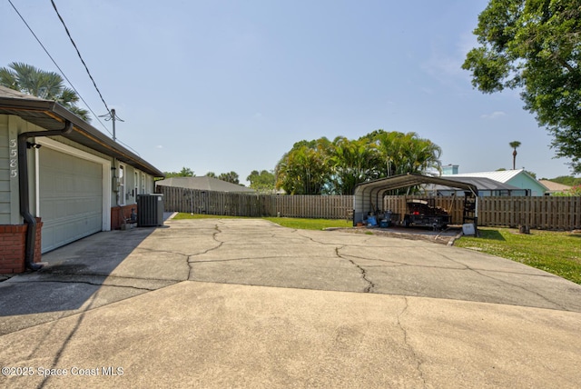 exterior space with fence, a garage, driveway, and a detached carport