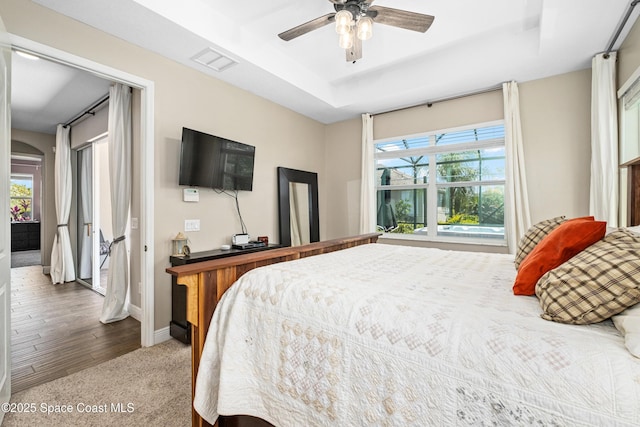 3631 Stabane Pl, Melbourne, FL 32940 - carpeted bedroom featuring a tray ceiling, baseboards, ceiling fan, and arched walkways