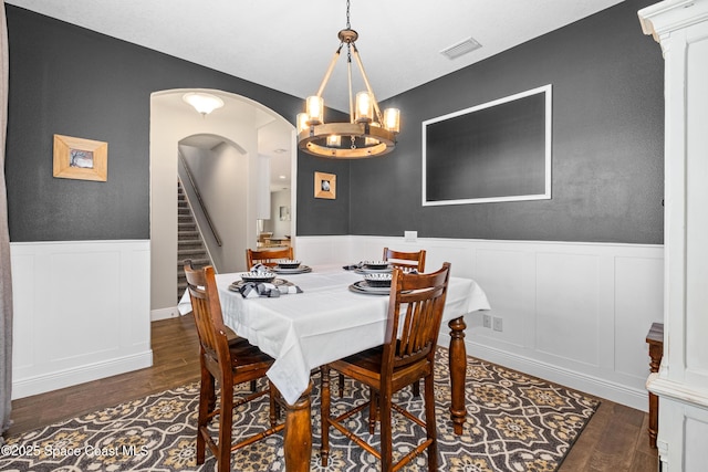 3631 Stabane Pl, Melbourne, FL 32940 - dining space featuring wood finished floors, a decorative wall, a wainscoted wall, stairs, and a chandelier
