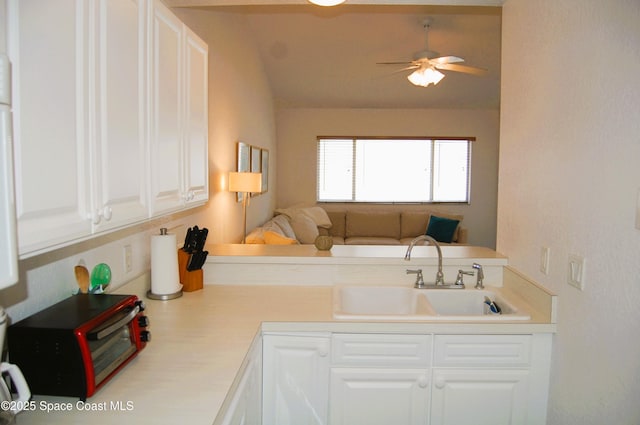 kitchen featuring a sink, light countertops, white cabinetry, open floor plan, and a ceiling fan