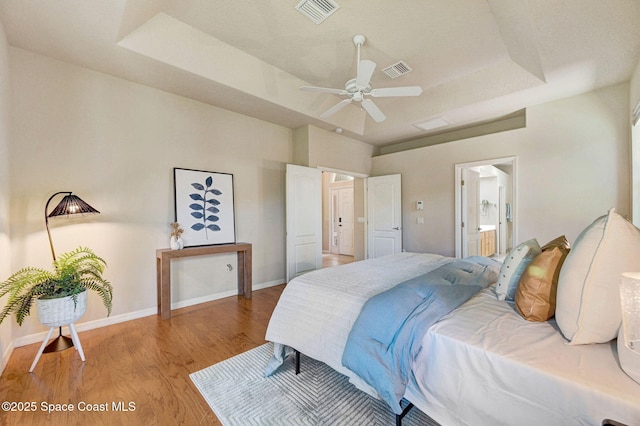 178 Cove Loop Dr, Merritt Island, FL 32953 - bedroom with light wood finished floors, a raised ceiling, baseboards, ensuite bathroom, and a ceiling fan