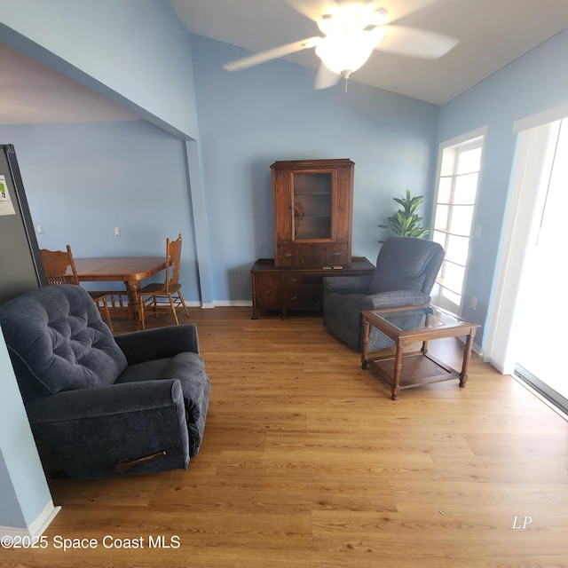 living area featuring lofted ceiling, ceiling fan, and light wood finished floors