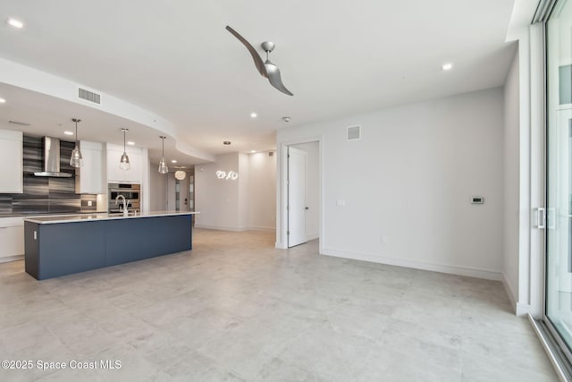unfurnished living room featuring recessed lighting, baseboards, and a sink