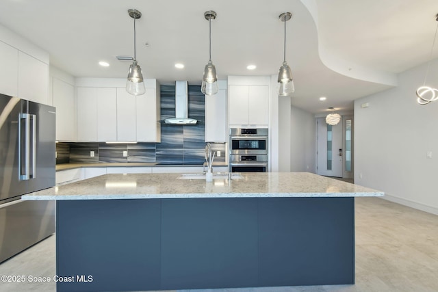 kitchen with stainless steel appliances, wall chimney exhaust hood, modern cabinets, backsplash, and a center island with sink