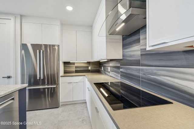 kitchen with freestanding refrigerator, wall chimney exhaust hood, white cabinets, black electric stovetop, and recessed lighting