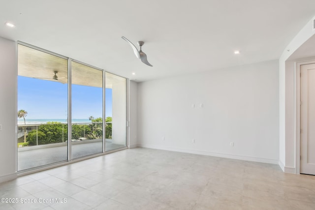 spare room with a wall of windows, baseboards, a water view, and ceiling fan