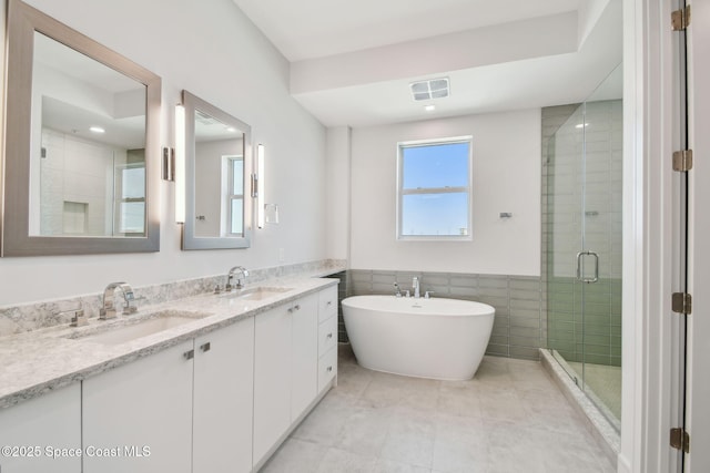 full bath featuring a shower stall, double vanity, tile walls, a soaking tub, and tile patterned flooring
