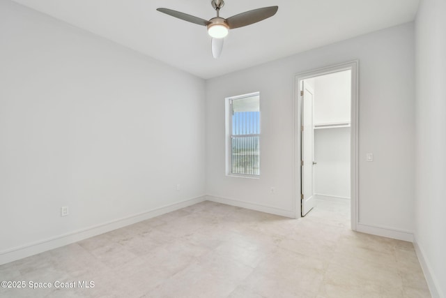 unfurnished bedroom with a spacious closet, baseboards, a closet, and a ceiling fan