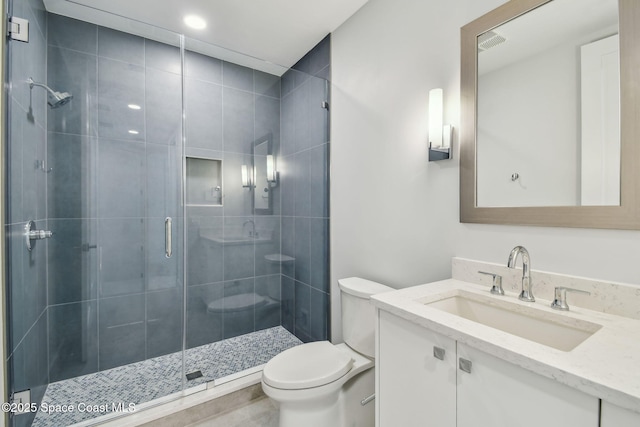 bathroom featuring toilet, a shower stall, and vanity