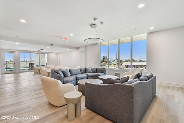 living area featuring healthy amount of natural light, light wood finished floors, and recessed lighting