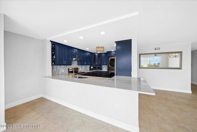 2203 Atlantic St Unit 715, Melbourne Beach, FL 32951 - kitchen featuring stacked washer and clothes dryer, blue cabinetry, a sink, a peninsula, and stainless steel appliances