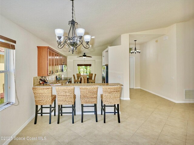 6227 Thames Pl, Vero Beach, FL 32966 - kitchen with a chandelier, stainless steel appliances, a kitchen breakfast bar, light tile patterned flooring, and a textured ceiling
