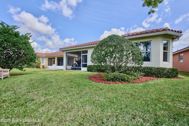 6227 Thames Pl, Vero Beach, FL 32966 - rear view of house with a tiled roof, a lawn, and a sunroom