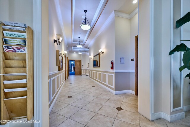 6227 Thames Pl, Vero Beach, FL 32966 - hall featuring crown molding, a decorative wall, light tile patterned flooring, wainscoting, and a high ceiling
