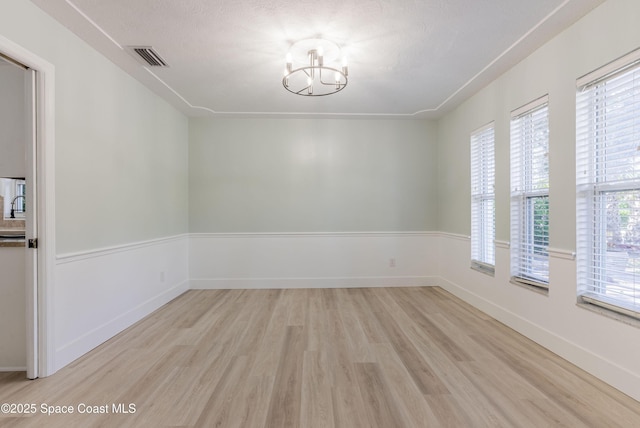 unfurnished room with light wood-type flooring, a chandelier, and baseboards