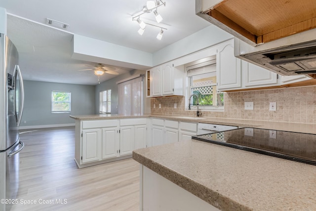 kitchen featuring a sink, a peninsula, stainless steel fridge, and light wood-style flooring