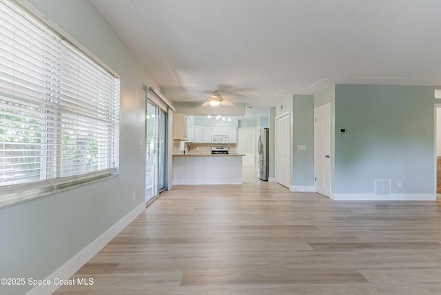 unfurnished living room featuring a ceiling fan, light wood finished floors, and baseboards