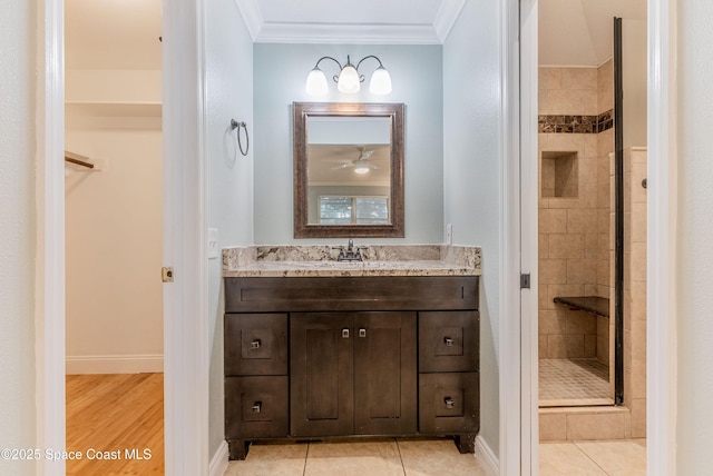 full bathroom featuring a stall shower, crown molding, vanity, a walk in closet, and tile patterned floors