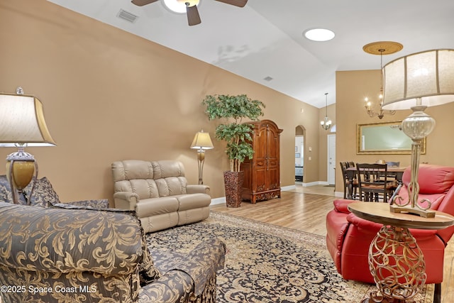 living room featuring ceiling fan, wood finished floors, arched walkways, high vaulted ceiling, and baseboards