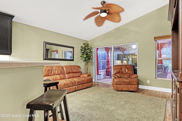 living room featuring lofted ceiling, a ceiling fan, wood finished floors, and baseboards