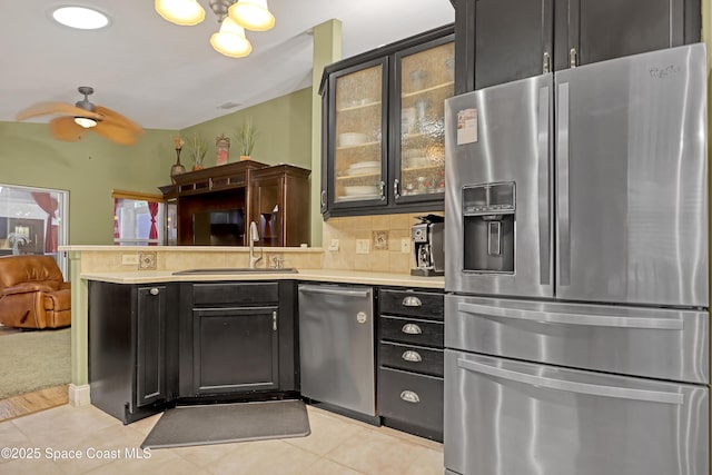 kitchen with stainless steel appliances, a sink, a peninsula, open floor plan, and light countertops