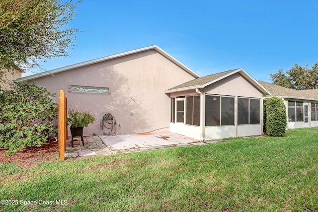 back of property featuring a sunroom, a patio, a yard, and stucco siding