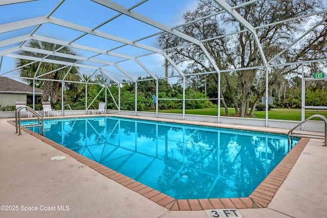 swimming pool with a patio, view of scattered trees, and glass enclosure