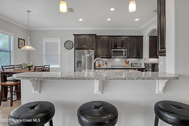 2922 Addison Dr, Melbourne, FL 32940 - kitchen with stainless steel appliances, a kitchen bar, dark brown cabinetry, decorative backsplash, and crown molding