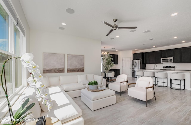 living room featuring a ceiling fan, recessed lighting, and a chandelier