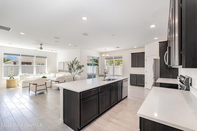 kitchen with stainless steel dishwasher, a sink, healthy amount of natural light, a kitchen island with sink, and recessed lighting