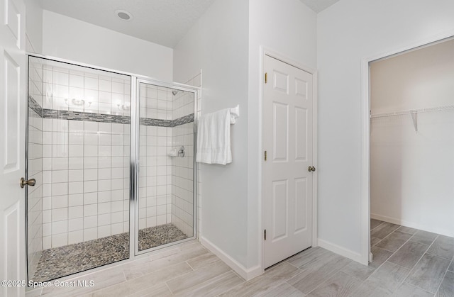 bathroom featuring a stall shower, wood finish floors, baseboards, and a closet