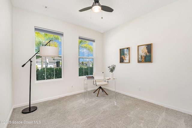 unfurnished room with carpet, a ceiling fan, baseboards, and a desk