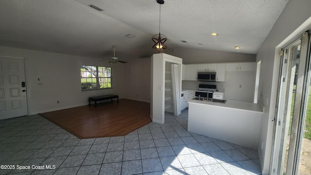kitchen featuring appliances with stainless steel finishes, light tile patterned floors, lofted ceiling, white cabinets, and light countertops