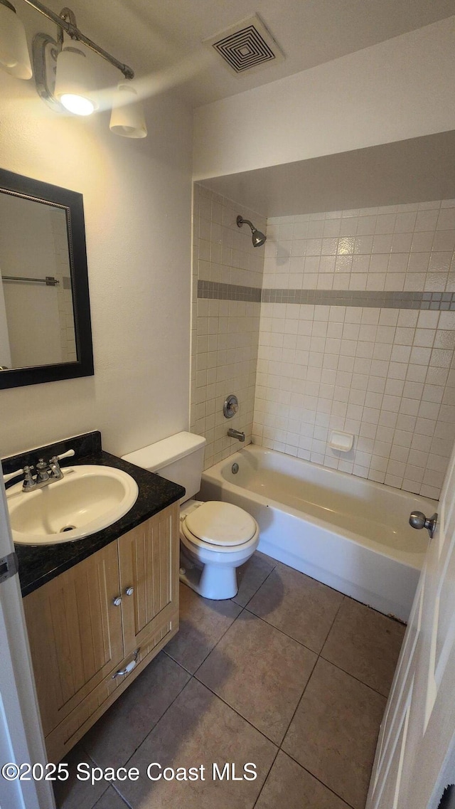 bathroom featuring tile patterned flooring, washtub / shower combination, vanity, and toilet