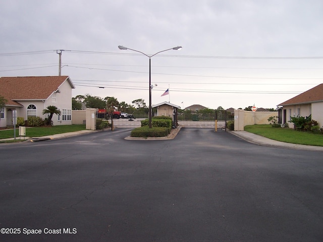 4077 Green Oak Dr, Melbourne, FL 32901 - view of asphalt road featuring a gate, sidewalks, street lighting, and curbs