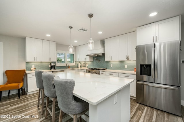 407 Sandpiper Dr, Satellite Beach, FL 32937 - kitchen with stainless steel appliances, custom range hood, wood finished floors, decorative backsplash, and recessed lighting