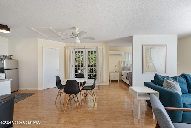 921 S Orlando Ave, Cocoa Beach, FL 32931 - dining room featuring a wall unit AC, a textured ceiling, a ceiling fan, light wood-style floors, and french doors
