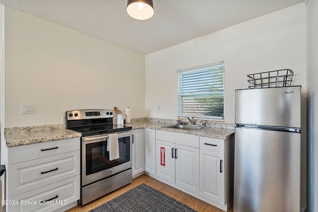 921 S Orlando Ave, Cocoa Beach, FL 32931 - kitchen with stainless steel appliances, a sink, light wood-style flooring, white cabinetry, and light stone countertops